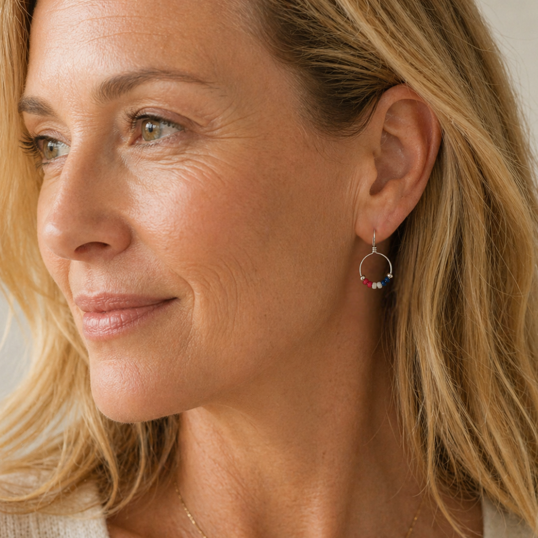 Close-up of a woman wearing red white and blue hoop earrings with a neutral background