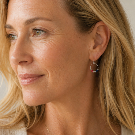 Close-up of a woman wearing red white and blue hoop earrings with a neutral background