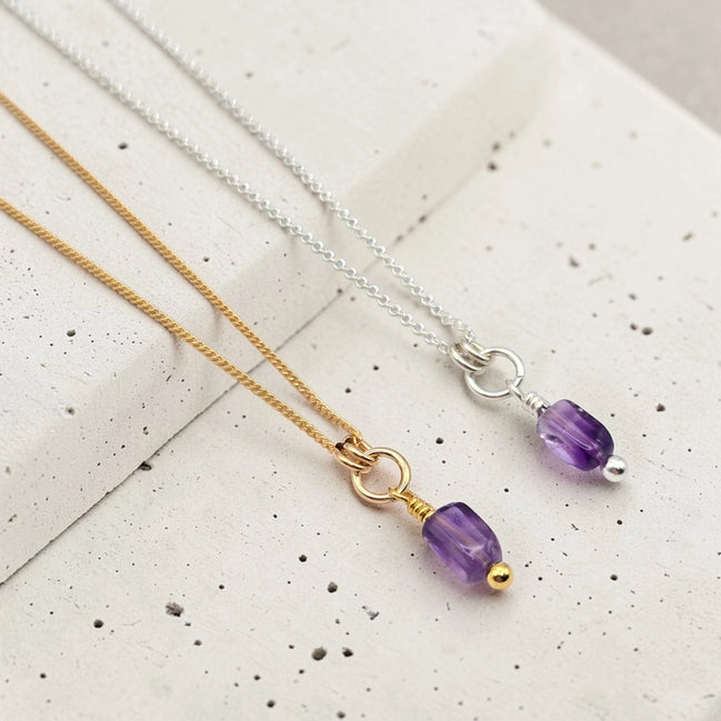 Two necklaces with purple beads on a textured surface