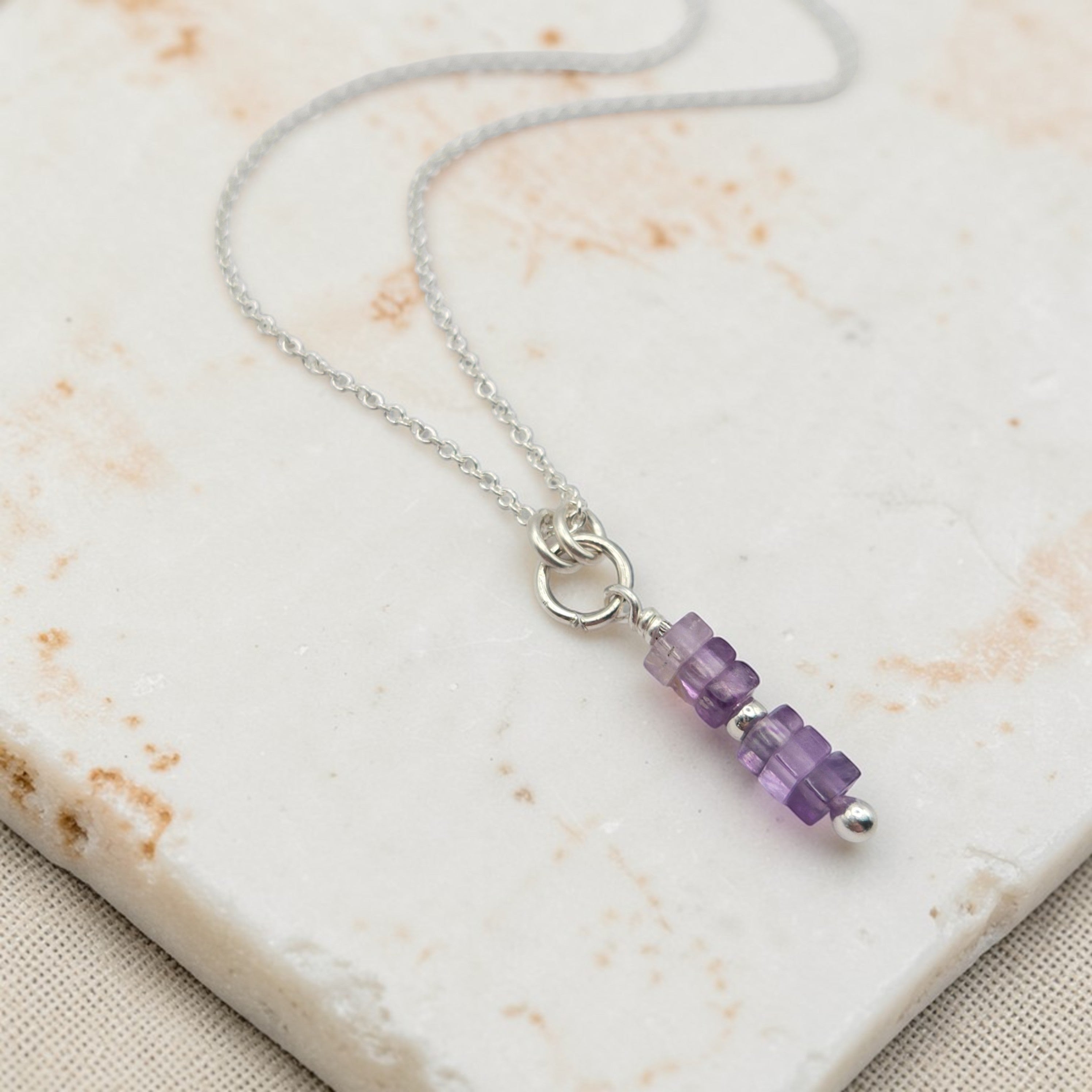 Necklace with purple beaded pendant on a marble surface