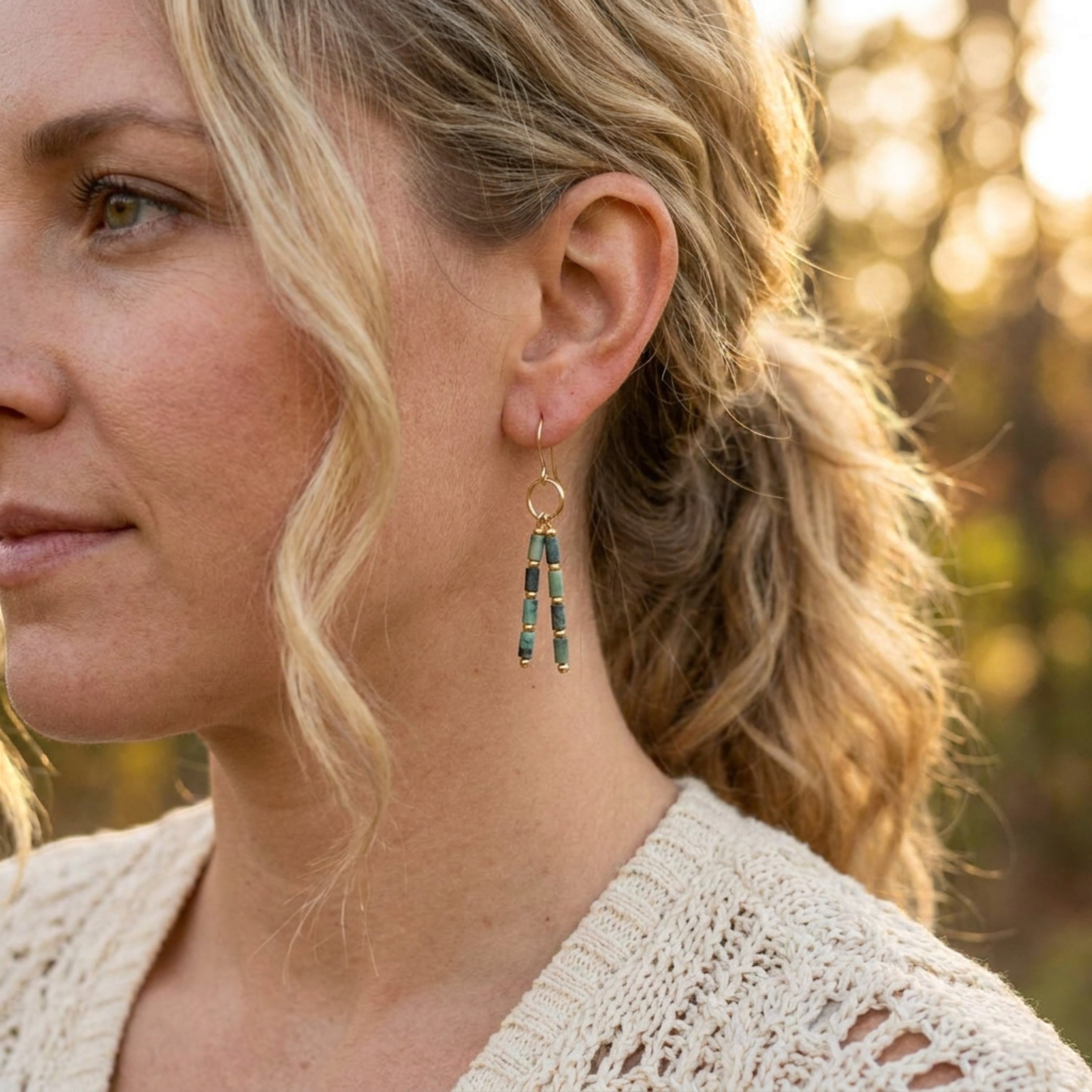 Bijou by SAM Mother Earth earrings featuring African Turquoise tube beads and gold hoops worn by a woman outdoors.