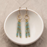 Bijou by SAM River Stone dangle earrings featuring Amazonite tube beads and 14k gold fill hoops on a white ceramic dish.