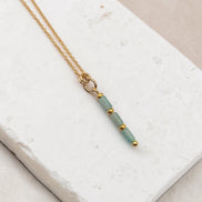Bijou by SAM River Stone necklace featuring natural Amazonite tube beads and 14k gold fill chain on a stone surface.