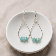 Bijou by SAM teardrop hoop earrings featuring aqua-green amazonite stones on sterling silver wires in a white bowl.