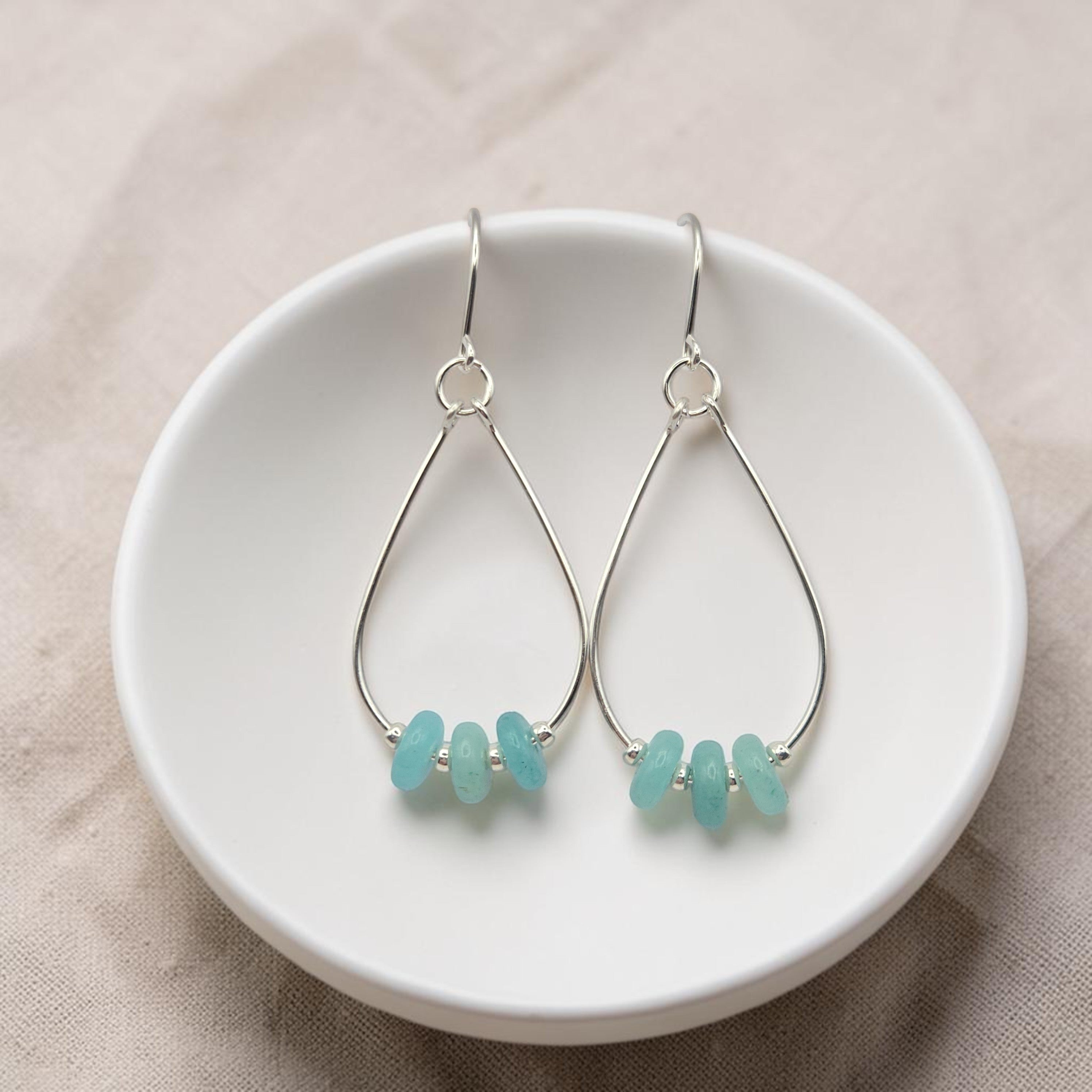 Bijou by SAM teardrop hoop earrings featuring aqua-green amazonite stones on sterling silver wires in a white bowl.