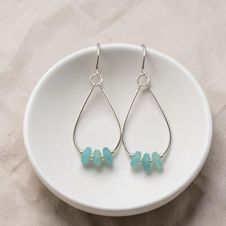 Bijou by SAM teardrop hoop earrings featuring aqua-green amazonite stones on sterling silver wires in a white bowl.