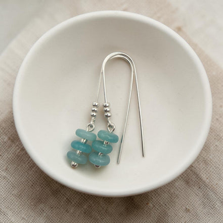 Bijou by SAM handmade threader earrings featuring aqua-green amazonite beads on sterling silver wire in a white bowl.