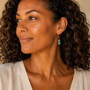 Bijou by SAM Northern Lights threader earrings featuring aqua-green amazonite beads worn by a woman with curly hair.