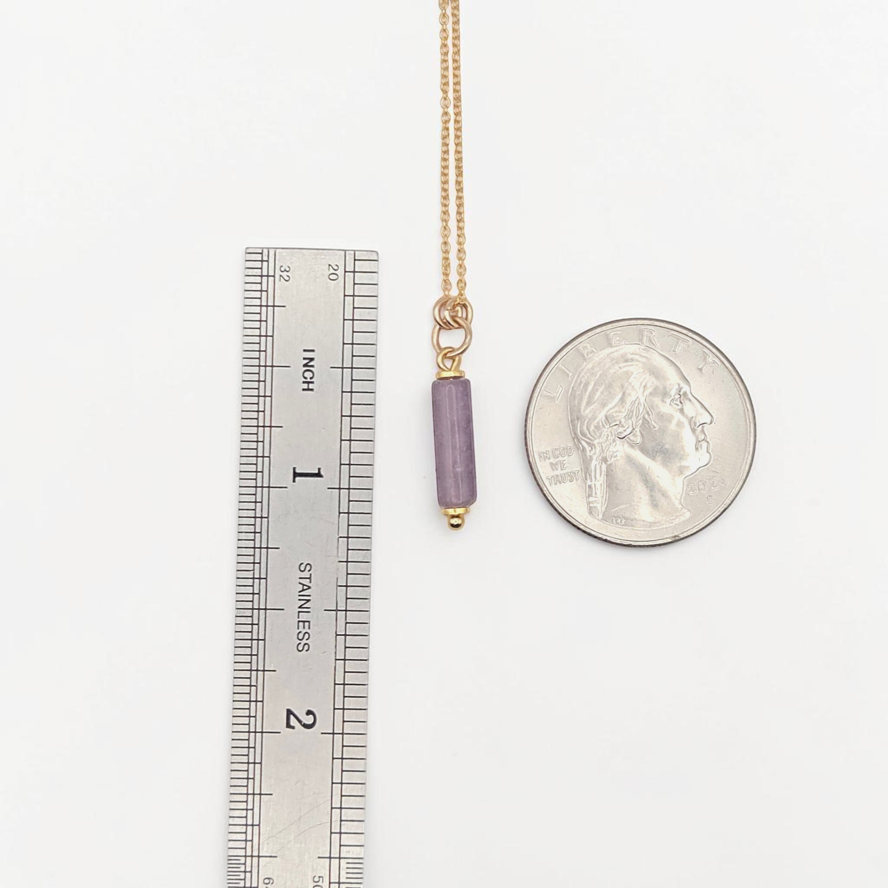 Bijou by SAM Sophia necklace featuring a purple amethyst cylinder bead on a delicate gold chain next to a coin