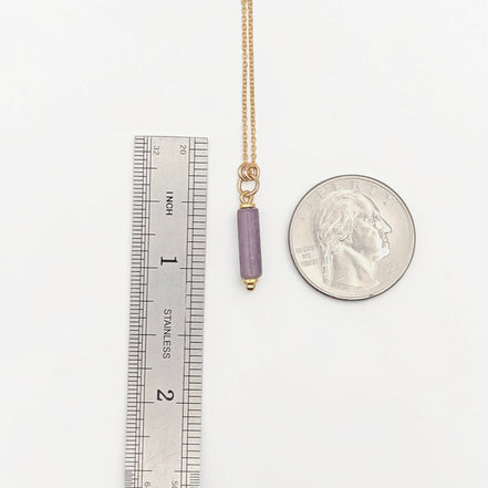 Bijou by SAM Sophia necklace featuring a purple amethyst cylinder bead on a delicate gold chain next to a coin
