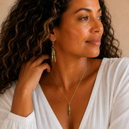 Bijou by SAM Big Sky earrings featuring aqua terra jasper tube beads on gold hoops worn by a woman in a white top