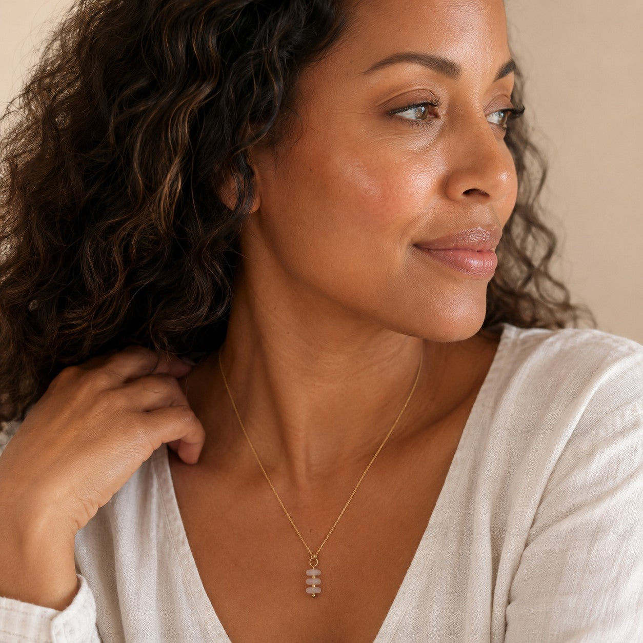 Bijou by SAM Aurora necklace featuring a delicate gold chain with three soft blush rose quartz beads on a woman.