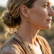 Bijou by SAM Canyon earrings featuring natural picture jasper tube beads and gold dangles worn by a woman outdoors.