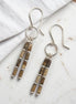 Bijou by SAM Canyon Earrings featuring natural Picture Jasper tube beads and sterling silver hoops on a marble surface.