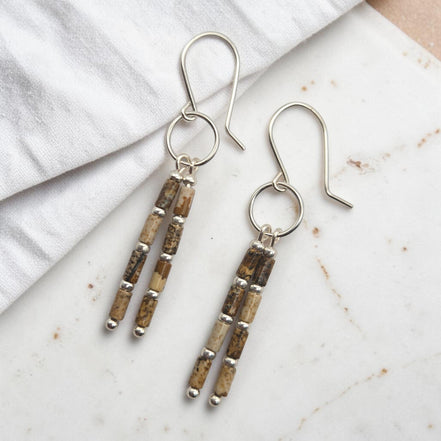 Bijou by SAM Canyon Earrings featuring natural Picture Jasper tube beads and sterling silver hoops on a marble surface.
