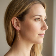 Bijou by SAM Canyon Teardrop Hoops featuring gold fill wire and picture jasper beads worn by a woman in profile.