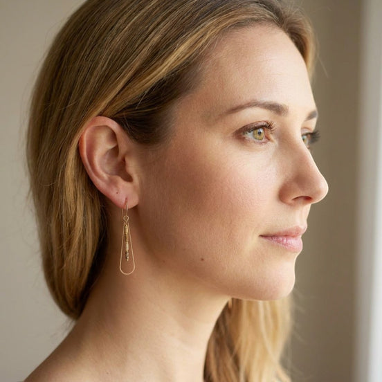Bijou by SAM Canyon Teardrop Hoops featuring gold fill wire and picture jasper beads worn by a woman in profile.