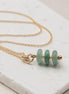 Bijou by SAM Comet necklace featuring three green aventurine stones on a delicate gold fill chain on a stone surface.