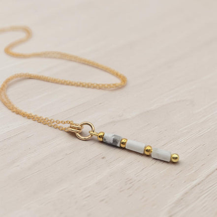 Bijou by SAM First Snow necklace with natural howlite tube beads and 14k gold fill chain on a light wooden surface.
