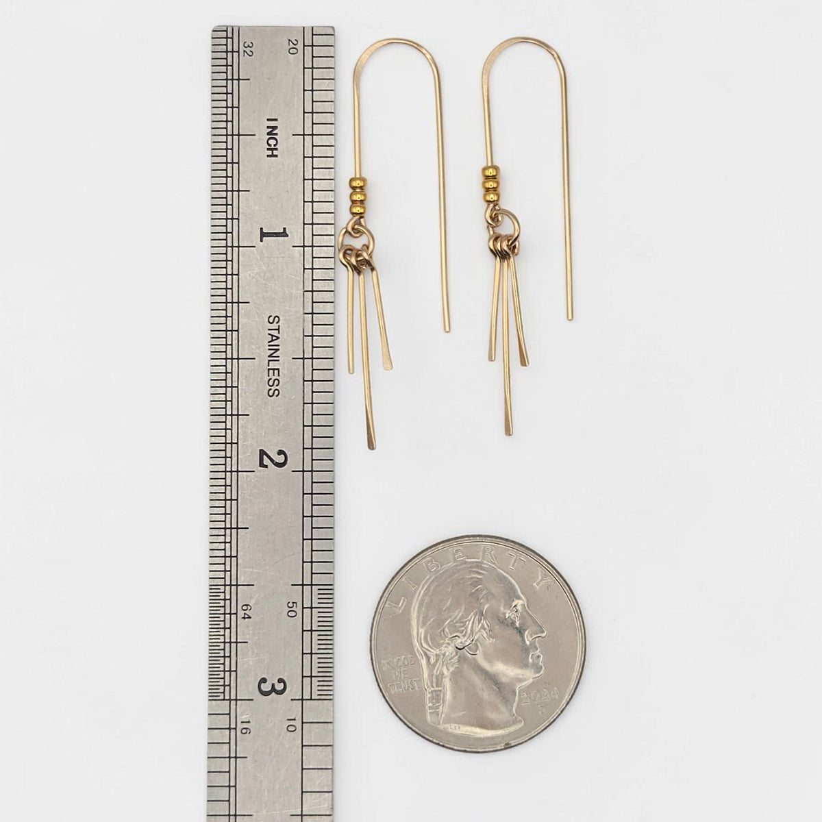 Bijou by SAM gold threader earrings featuring three delicate metal fringes, shown next to a ruler and US quarter.