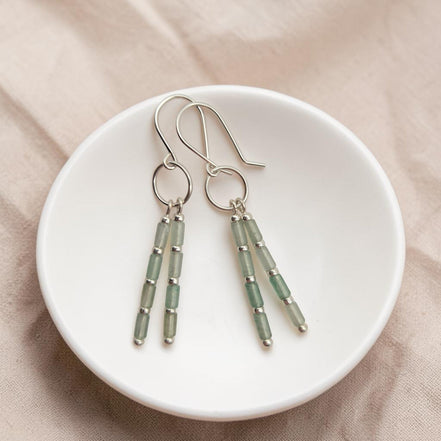 Bijou by SAM Mossy Creek earrings featuring green aventurine tube beads and sterling silver hoops in a white bowl.