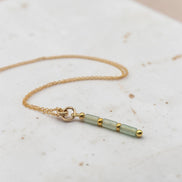 Bijou by SAM Mossy Creek necklace featuring green aventurine tube beads and 14k gold fill chain on a stone surface.