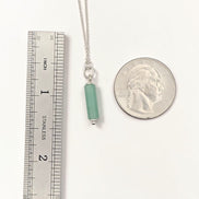 Bijou by SAM Ava necklace featuring a green aventurine cylinder bead on a delicate sterling silver chain next to a coin.