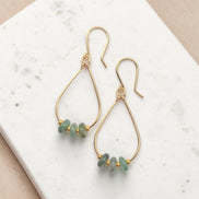 Bijou by SAM Comet Teardrop Hoop Earrings featuring green aventurine stones on 14k gold fill wire on a white surface.