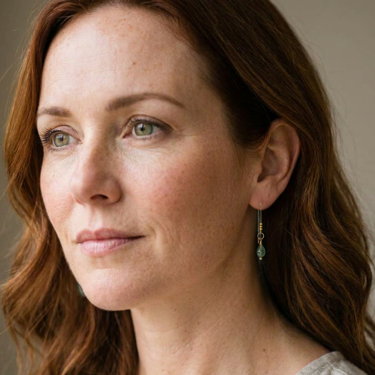 Bijou by SAM teardrop green aventurine threader earrings worn by a woman with auburn hair and green eyes.
