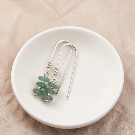 Bijou by SAM Comet threader earrings featuring green aventurine beads on sterling silver wire in a white dish.