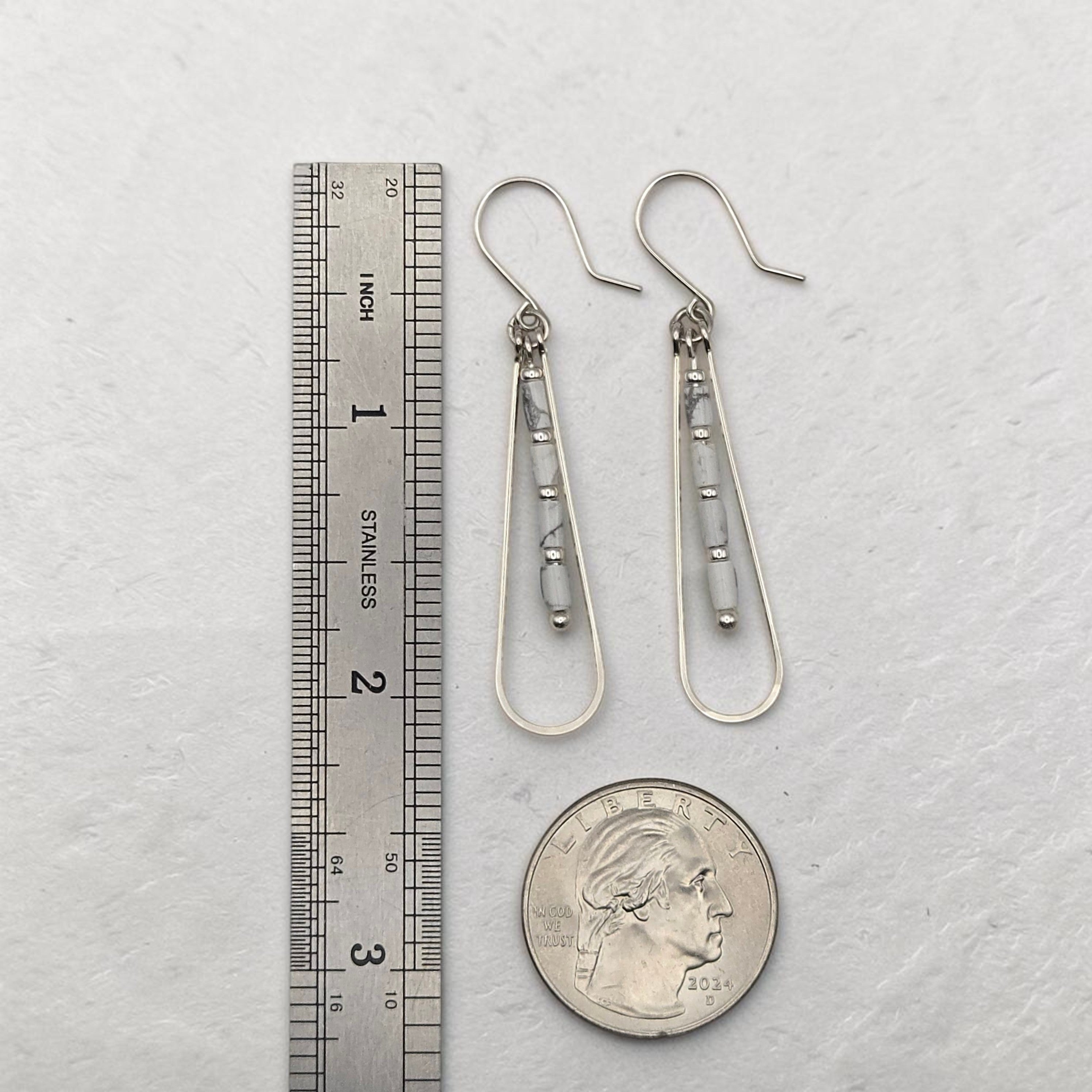Bijou by SAM First Snow teardrop earrings with white Howlite tube beads and sterling silver hoops next to a ruler.