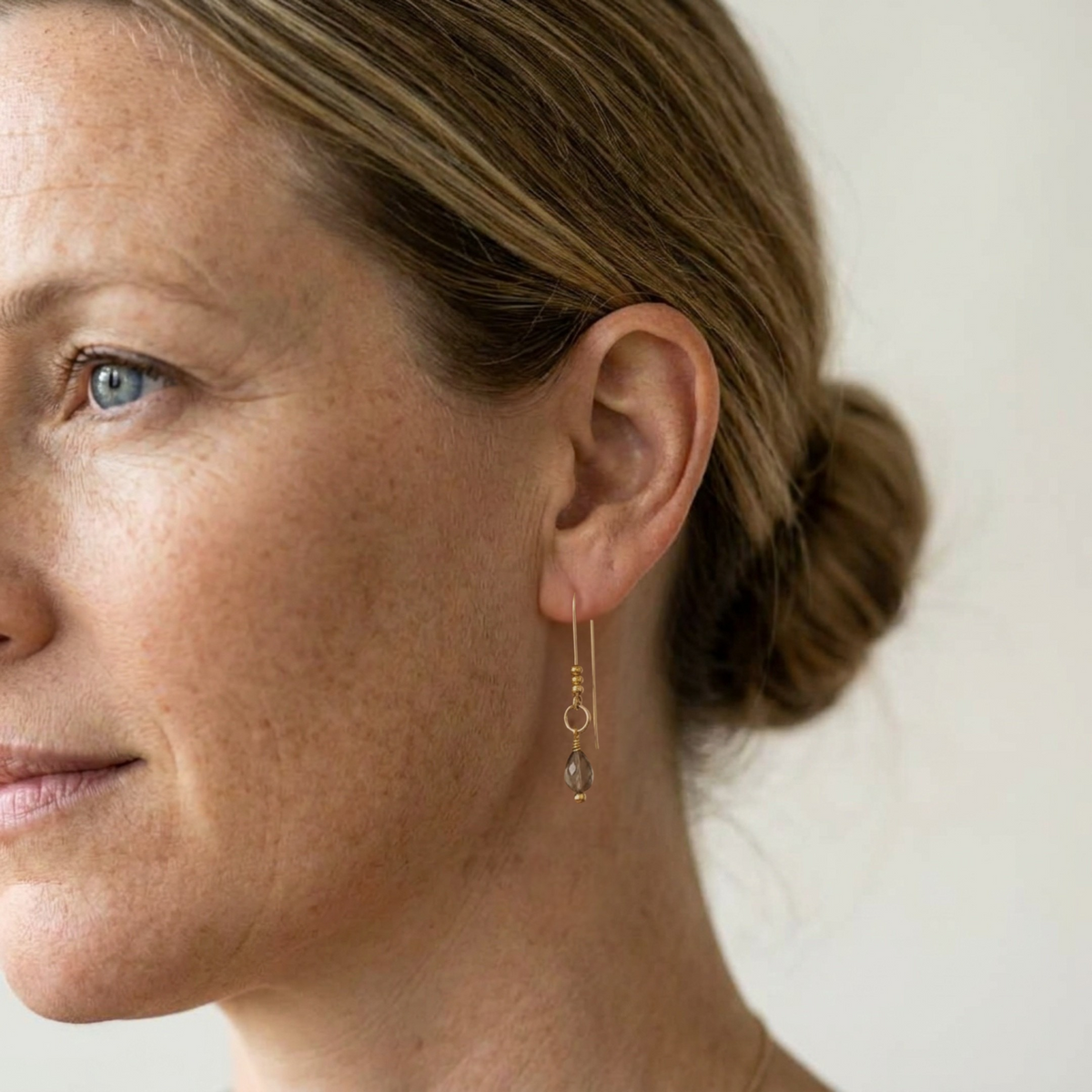 Bijou by SAM gold threader earrings featuring a delicate teardrop Ice Obsidian gemstone worn by a woman.