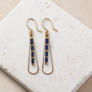 Bijou by SAM Midnight Sky teardrop earrings with blue Lapis Lazuli beads and 14k gold fill hoops on a stone surface.