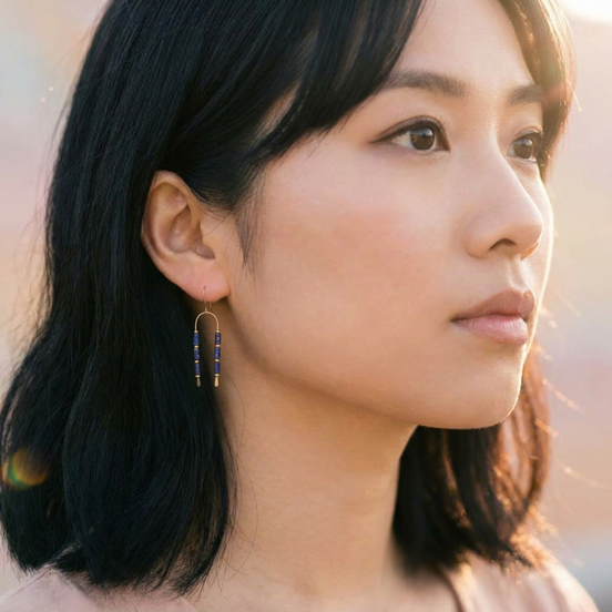 Bijou by SAM wishbone earrings featuring blue lapis lazuli tube stones on gold wire worn by a woman