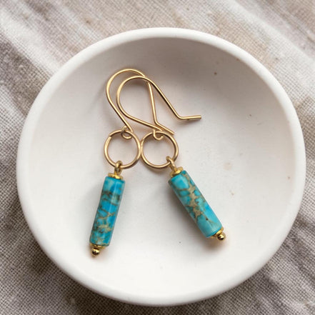 Bijou by SAM Mia earrings featuring turquoise jasper cylinders on handcrafted 14k gold fill hoops in a white bowl.