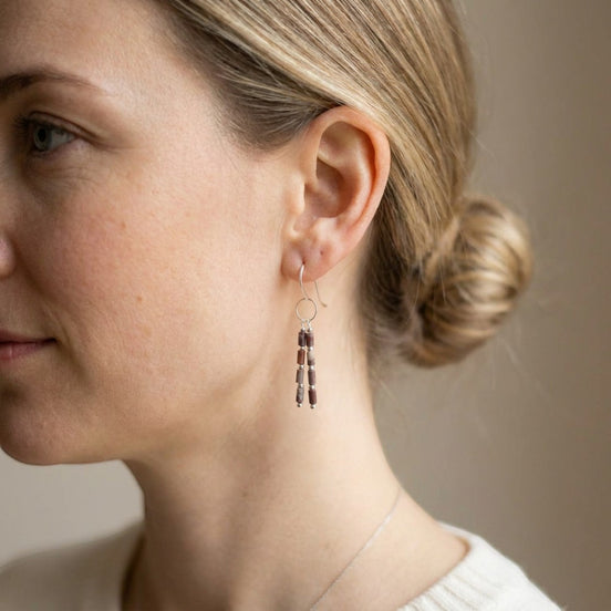 Bijou by SAM Painted Bluff earrings featuring red rainbow jasper tube beads on sterling silver dangles worn by a woman.