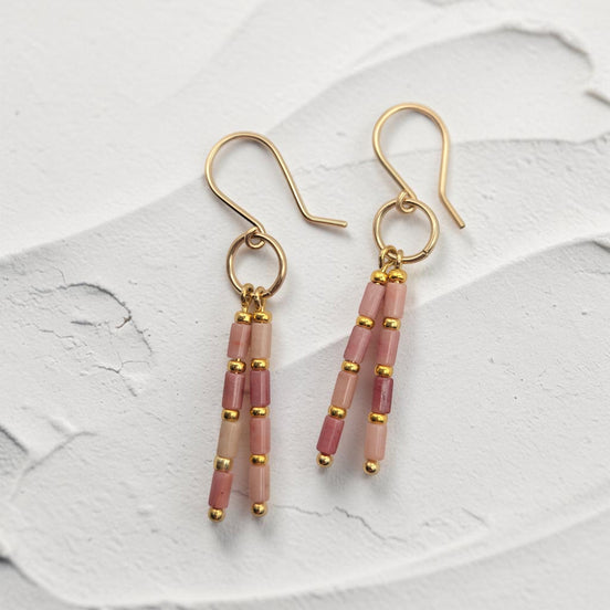 Bijou by SAM Rose Bluff earrings featuring pink rhodonite tube beads and 14k gold fill hoops on a white textured base.