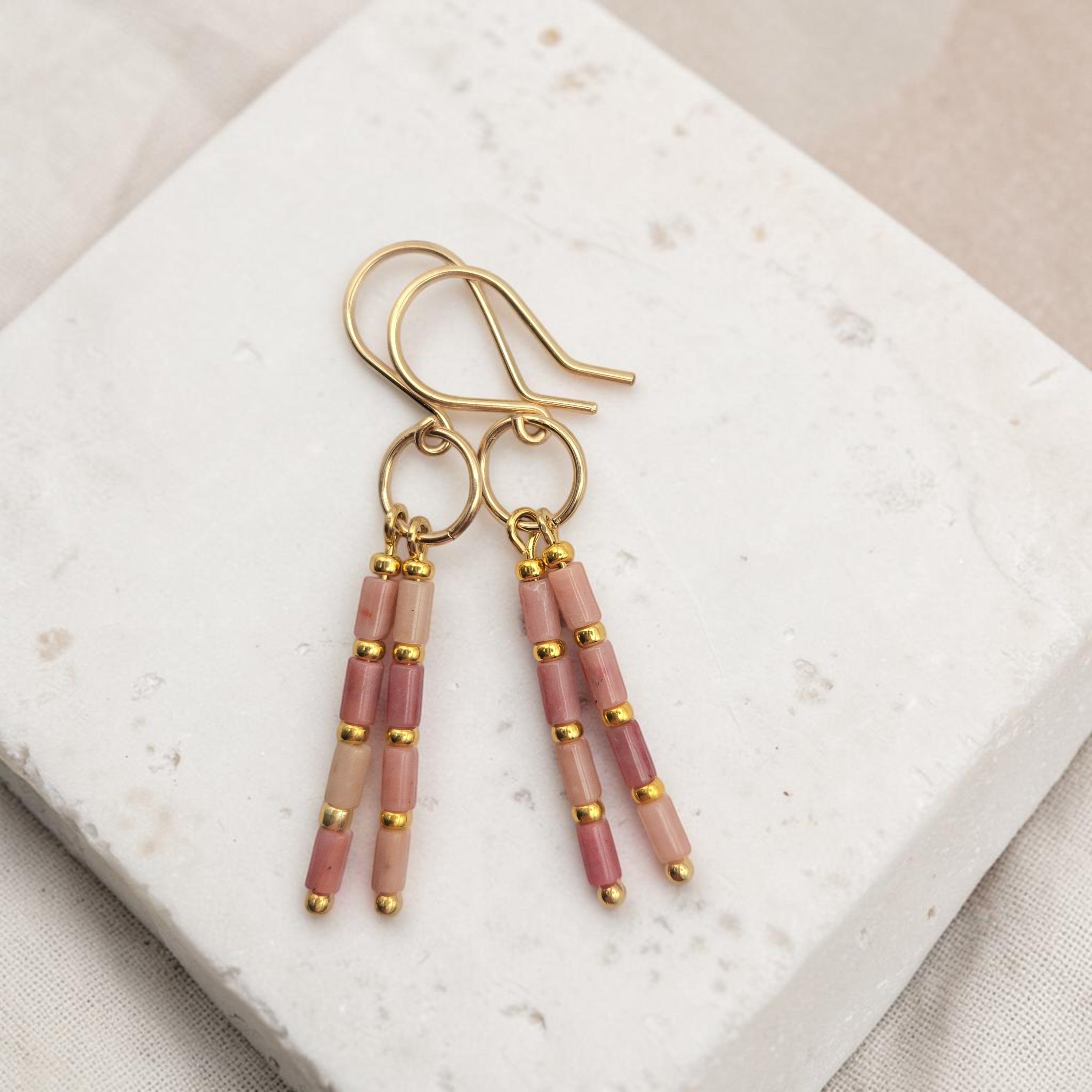 Bijou by SAM Rose Bluff earrings featuring pink rhodonite tube beads and 14k gold fill hoops on a stone display.