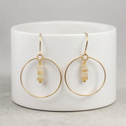 Bijou by SAM handmade gold hoop earrings featuring delicate square-cut rutilated quartz stones on a white stand.