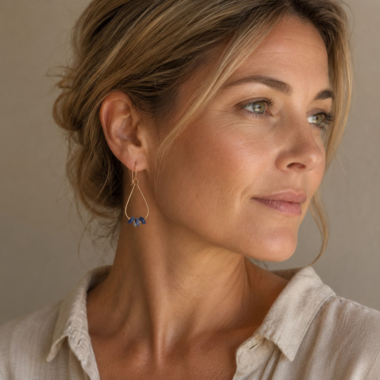 Bijou by SAM Milky Way teardrop hoop earrings featuring blue sodalite stones on 14k gold fill worn by a woman.
