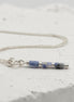 Bijou by SAM Stone Creek necklace featuring blue spot jasper tube beads and sterling silver chain on white stone.
