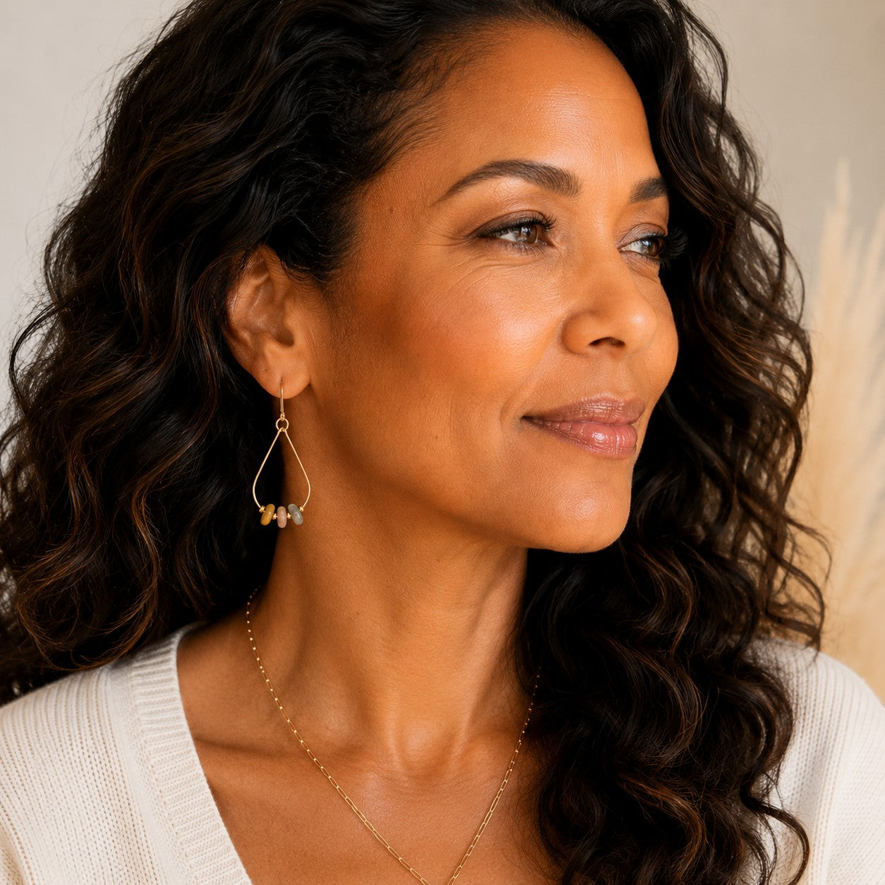 Bijou by SAM Stardust teardrop hoop earrings featuring crazy lace agate stones on a model wearing a white sweater.