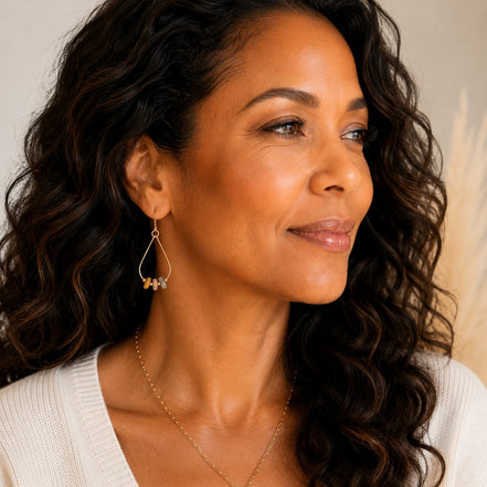 Bijou by SAM Stardust teardrop hoop earrings featuring crazy lace agate stones on a model wearing a white sweater.