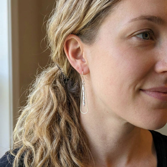Bijou by SAM First Snow teardrop earrings with white Howlite beads and silver hoops worn by a woman