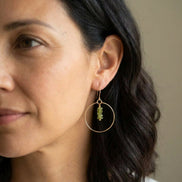 Bijou by SAM handmade gold hoop earrings featuring a delicate stack of square-cut green Vesuvianite stones on a model