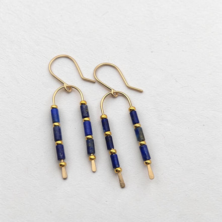 Bijou by SAM wishbone earrings featuring blue lapis lazuli tube stones and 14k gold fill wire on a white background.