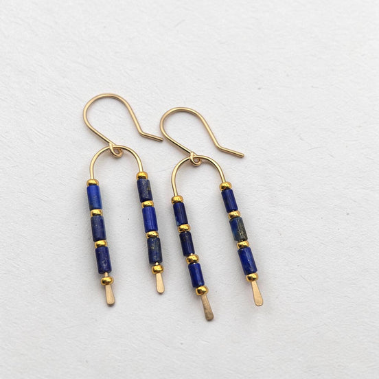 Bijou by SAM wishbone earrings featuring blue lapis lazuli tube stones and 14k gold fill wire on a white background.