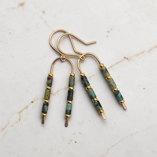 Bijou by SAM wishbone earrings featuring African Turquoise tube stones and 14k gold fill wire on a marble surface.