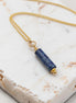 Necklace with a blue cylindrical pendant on a marble surface
