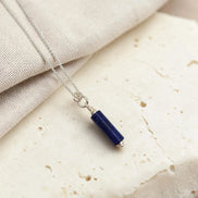 Necklace with a blue pendant on a beige fabric background